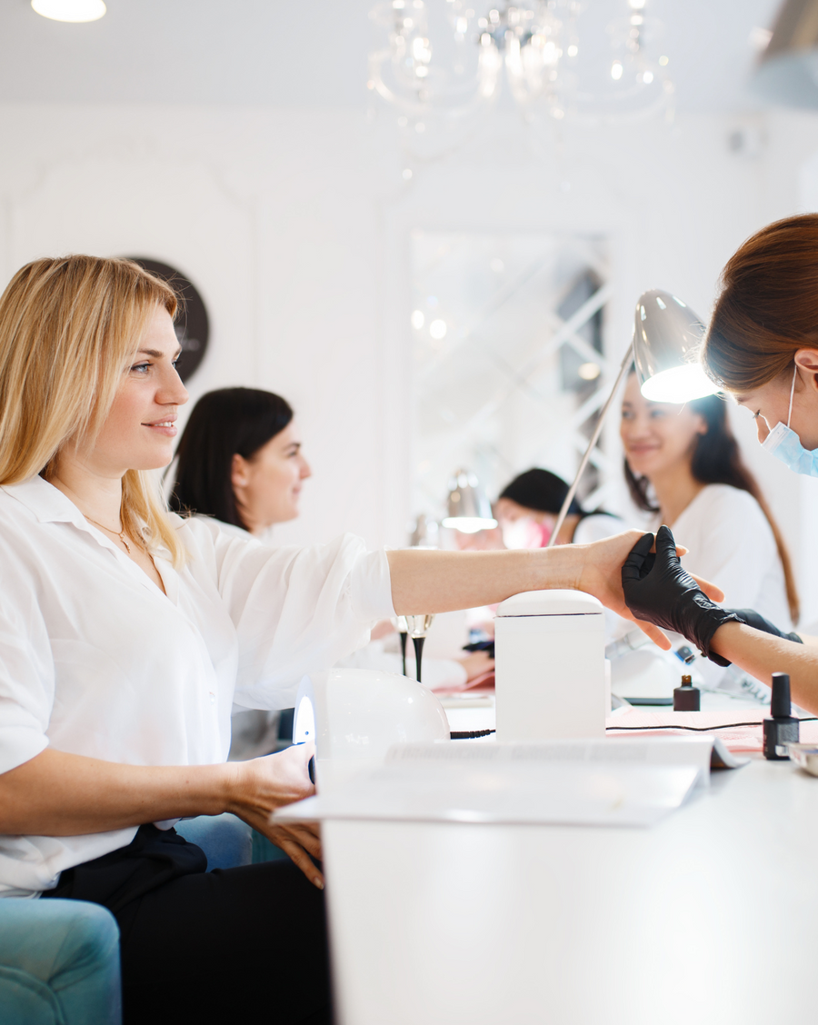 Nail techs working with clients in a bright salon